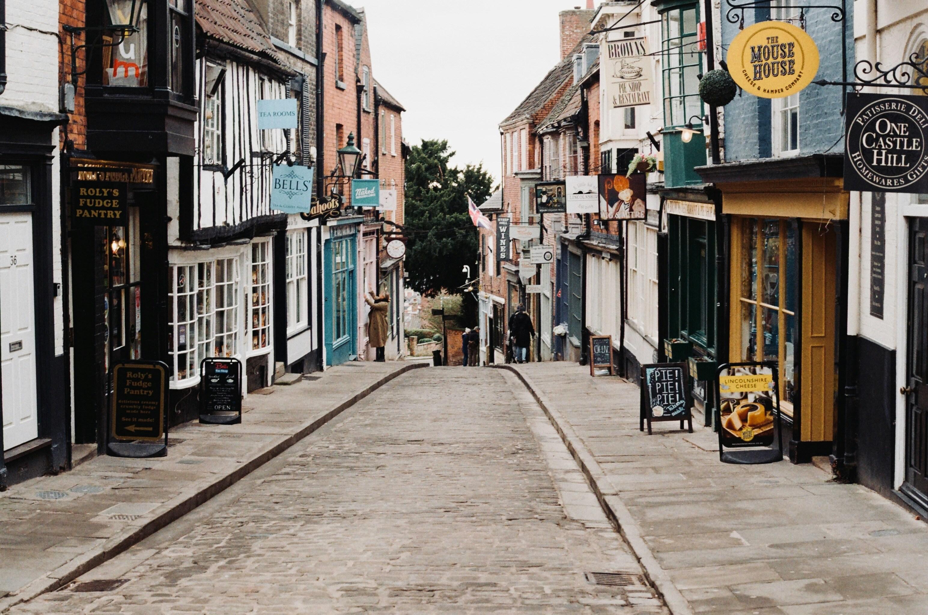 Look down Lincoln’s Steep Hill shopping area; there is a road in the middle and independent shops on each side of the road.