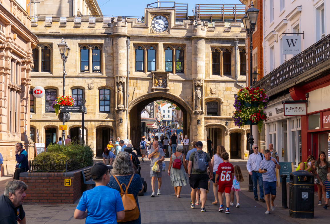 A bright photo taken in summer of people walking by the Guildhall.