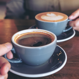 Two people holding cups of coffee.